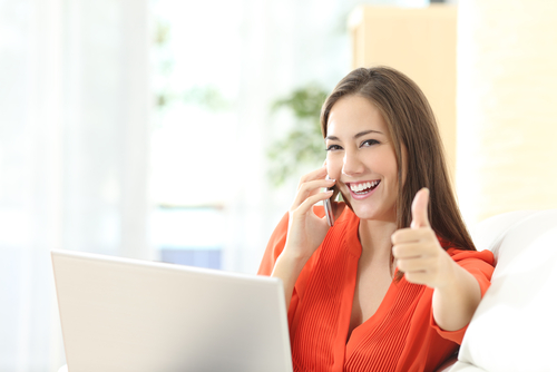 A woman in front of a computer giving a thumbs up after great service.