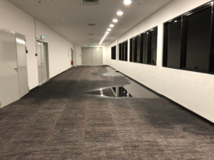 A hallway of a commercial building that is experiencing flooring from a broken pipe.