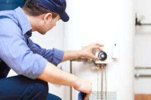 A male plumber adjusting water heater settings.